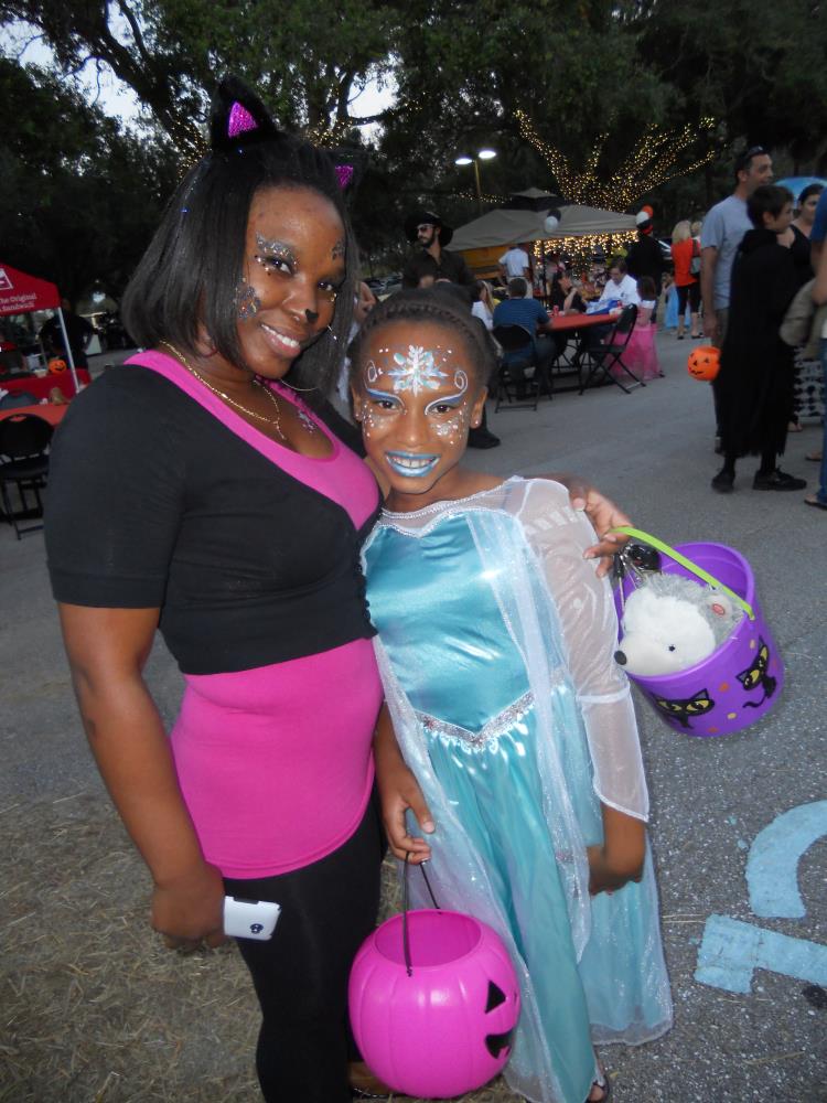 Woman dressed in cat outfit taking picture with girl in blue princess outfit
